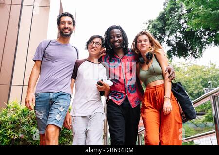 Eine Gruppe junger Menschen verschiedener Ethnien, die auf der Straße zusammen stehen und lächeln Stockfoto
