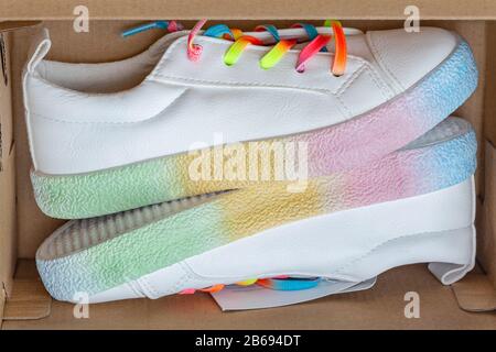 Weiße Sneaker mit Regenbogenschnürsenkeln sind in einer braunen Schachtel Stockfoto