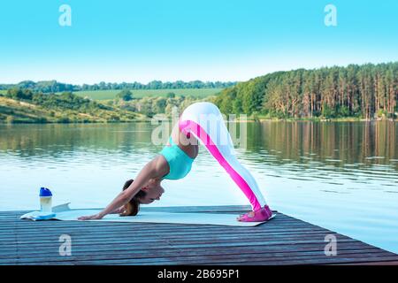 Ein wunderschönes Mädchen führt eine Yoga-Übung namens "Spinnen Nach Vorne", Sanskritname: Uttanasana, durch. Diese Pose streckt den Rücken der Beine, Hüften, Wirbelsäule, Stockfoto