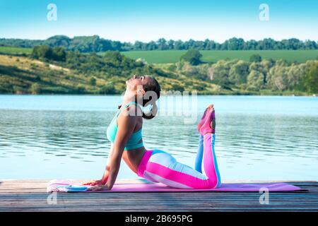 Schöne Mädchen üben Yoga auf dem Hintergrund der schönen Natur. Pilates. Gesundes Lifestyle-Konzept Stockfoto