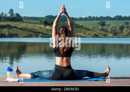 Rückansicht der Jungen Frau, die Yoga-Übungen macht. Sitzend in der Übung Sukhasana, Easy Seat Pose.Konzept für Sport, Gesundheitswesen Stockfoto