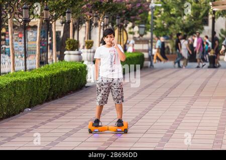Istanbul, TÜRKEI - 10. SEPTEMBER 2017: Teenager-Junge, der auf Hoverboard oder Gyroscooter im Park reitet und mit dem Handy spricht Stockfoto