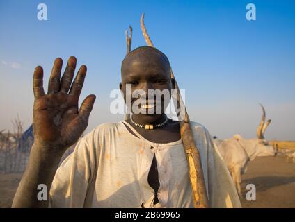 Lächelnder Mundari-Stammjunge winkt Hand, um in einem Viehlager, Central Equatoria, Terekeka, Südsudan, Hallo zu sagen Stockfoto