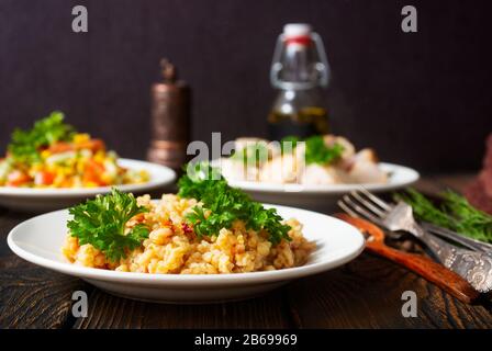 Huhn geröstet mit Gemüse- und Bulgur-Sauce und frischem Gemüsesalat auf Holzgrund Stockfoto