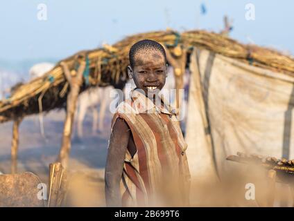 Lächelnder mundarischer Stammjunge, der mit Asche bedeckt ist, um Fliegen und Mücken in einem Viehlager, Central Equatoria, Terekeka, Südsudan abzuwehren Stockfoto