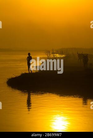 Stammkind der Mundari am Nilufer bei Sonnenuntergang, Central Equatoria, Terekeka, Südsudan Stockfoto