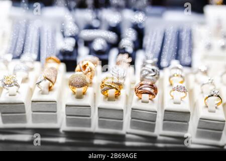 Verschiedene goldene Ringe mit kostbaren Edelsteinen im Juweliergeschäft, Fensterabschluss Stockfoto