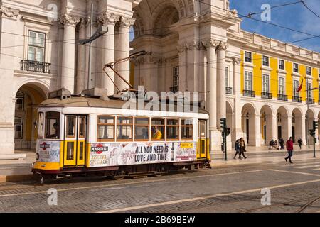 Lissabon, Portugal - 2. März 2020: Berühmte gelbe Straßenbahn 28 am Praca do Comercio vor Arco da Rua Augusta Stockfoto