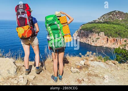 Zwei glückliche Wanderer mit Rucksäcken, die den Lykischen Weg gehen und sich in einer einsamen Lagune mit herrlichem Blick auf das Mittelmeer entspannen Stockfoto