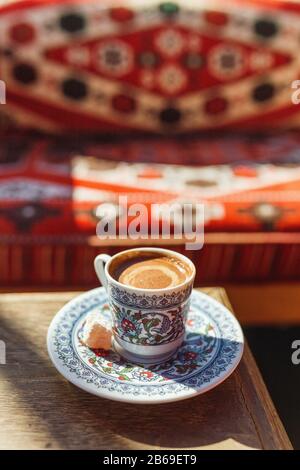 Authentischer türkischer Kaffee in einem Becher mit nationalen Mustern auf einem Holztisch in einem lokalen Restaurant Stockfoto