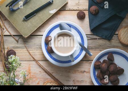 Tasse Kaffee neben einigen Noten und eine Feder auf einem rustikalen Holztisch im Alter. Leeren Sie den Kopierbereich für den Text des Editors. Stockfoto