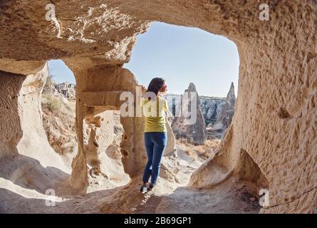 Frau des Reisenden, die in einer unterirdischen Stadt in Kappadokien, Türkei, steht. Konzept der Archäologie und Touristenziel Stockfoto