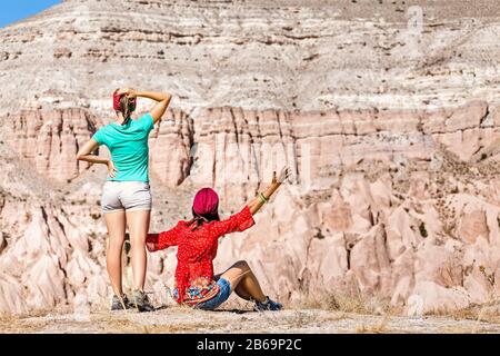 Zwei glückliche aktive Frauen, die gemeinsam in einem Felsschlucht aus Sandstein in der Wüste wandern, Reise- und Urlaubskonzept Stockfoto