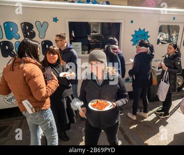 Besucher des Warby Parker Brillenglasgeschäfts in Soho in New York genießen am Samstag, 7. März 2020 kostenlose Pizza, um das zehnjährige Jubiläum des Optikgeschäfts bei einer Branding-Veranstaltung zu feiern. Der Brillenkaufmann tritt in die Fußstapfen anderer E-Commerce-Unternehmen, um zu finden, dass sie eine physische Präsenz benötigen, um Kunden zu bedienen und anzuziehen. (© Richard B. Levine) Stockfoto