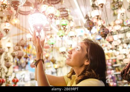 Frau, die am Istanbul Bazaar einkauft und sich für eine traditionelle türkische Erinnerungslampe entscheidet Stockfoto