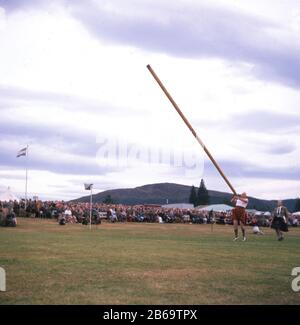 1960er Jahre, historisch, ein Wettstreiter in einem Kilt, der das Schwert wirft, ein traditionelles starkes Mann-Event bei den Scottish Highland Games, Schottland, Großbritannien. Ein großer, sich verjüngender Stab wird normalerweise aus der Lärche hergestellt und kann bis zu 150 kg wiegen. Stockfoto