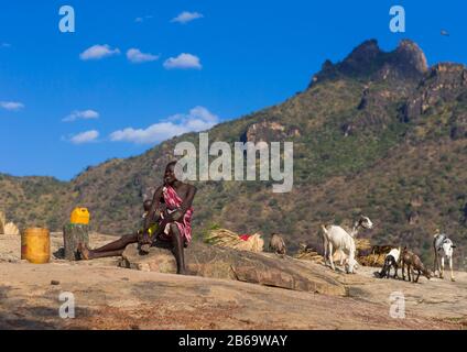 Larim-Stammfrau sitzt auf einem Felsen vor den Hügeln, Boya-Bergen, Imatong, Südsudan Stockfoto