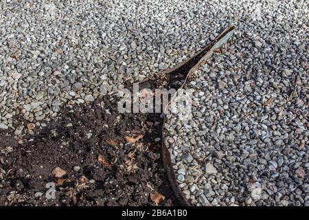 Metalleinkantung, die Schmutz und verschiedene Schotterfarben in einem Park voneinander trennt Stockfoto