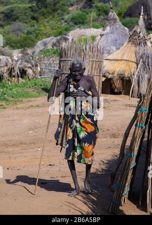 Alte Frau, die in einem traditionellen Dorf des Larim-Stammes, Boya Mountains, Imatong, Südsudan, vorbeigeht Stockfoto