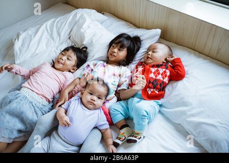 Vier asiatische Kinder spielen gern und scherzten im Bett, wenn sie aufwachen