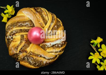 Traditionelle europäische Ostern Kranz Osterkranz Bäckerei mit Walnüssen einen Kranz mit einem Osterei in der Mitte und Narzissen Narzissen Stockfoto