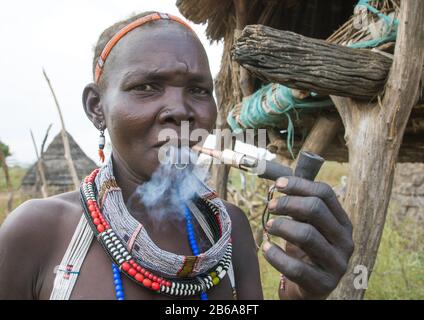 Toposa-Stammfrau raucht Pfeife in einem Dorf, Namorunyang State, Kapoeta, Südsudan Stockfoto