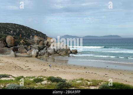 Ein Paar am Strand am Whisky Beach. Massive Felsbrocken aus Granit schmücken die Küste wie Naturplastiken Stockfoto