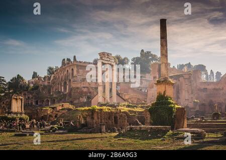 Die berühmten und alten Tempelruinen auf dem römischen Forum in Rom, Italien. Die Sonne beginnt sich zu stellen und erzeugt einen hellen Dunst und pinkige Farben. Stockfoto