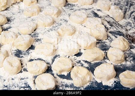 Hausgemachte Dnocchi. Ungekochte Gnocchi auf tiefblauem Tisch. Rohe, trickige Gebäckstücke in Mehl. Italienische Küche. Stockfoto