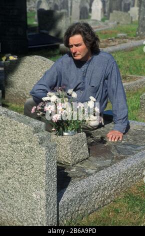 Mann an Grabseite auf dem Friedhof Stockfoto