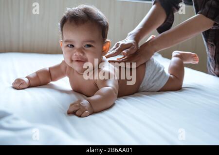 Bauchbaby Happy lächelt seine Mutter beim liegen im Schlafzimmer mit dem Rücken Stockfoto