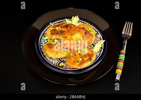 Teller mit hausgemachtem gebratenem Erbsenchikpea brüttert auf schwarzem Hintergrund. Vegetarische Mahlzeit. Gesundes Konzept für organische Lebensmittel Stockfoto