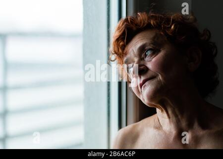 Frau am Fenster, die über das Leben nachdenkt Stockfoto