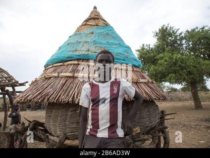 Toposa-Stammjunge mit einem Juventus-Fußballtrikot in der Nähe einer Granary, Namorunyang State, Kapoeta, Südsudan Stockfoto