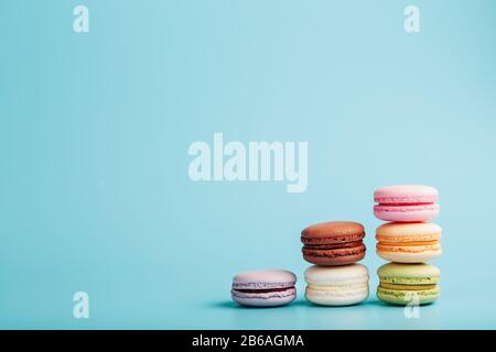 Mehrfarbige französische Makaroni Makaroni Kekse sind in einer Pyramide auf blauem Grund angeordnet. Freier Speicherplatz, Nahaufnahme. Minimalistisches Konzept Stockfoto