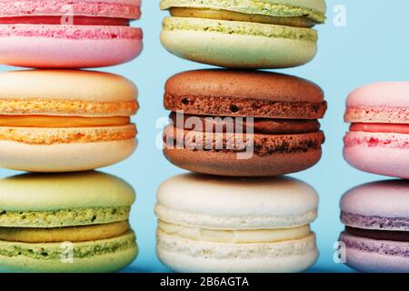 Mehrfarbige französische Makaroni Makaroni Kekse sind in einer Pyramide auf blauem Grund angeordnet. Freier Speicherplatz, Nahaufnahme. Minimalistisches Konzept Stockfoto