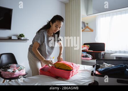 Asiatische Mutter bereitet Kleidung und Taschen für Urlaubsreisen vor Stockfoto