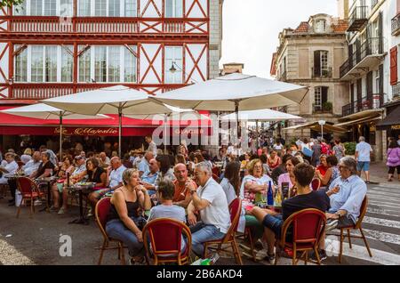 Saint Jean de Luz, französisches Baskenland, Frankreich - 13. Juli 2019: Die Leute sitzen auf der Außenterrasse des Cafe Majestic im Place Louis, 14:00 Uhr Stockfoto