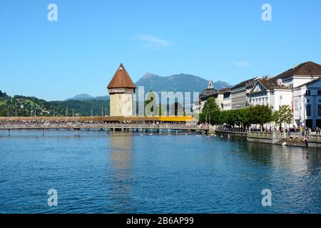 Luzerne, SCHWEIZ - 3. JULI 2014: Kapellenbrücke am Fluss Reuss. Berge, Hotels und der Bahnhof stehen im Hintergrund. Stockfoto