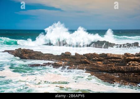 Die Wellen krachen wild am felsigen Ufer an Storms River Mouth, Tsitsikampa National Park, Südafrika Stockfoto