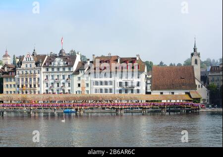 Luzerner, SCHWEIZ - 2. JULI 2014: Hotels führen am Ufer des Flusses Reuss in Luzerne, Schweiz. Die Kapellenbrücke überquert den Fluss vor dem Stockfoto