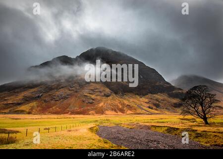 Ein stimmungsvoller Blick auf einen felsigen Hügel in Glencoe, mit Rot, Orange und Grün. Schottland. Stockfoto