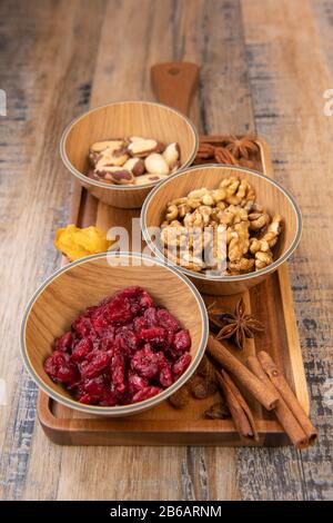 Gemischte Nüsse und getrocknete Früchte in Holzschale auf Holzhintergrund, Kopierraum Stockfoto