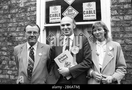 1987, historischer, SDP-liberaler politischer Kandidat Vince Cable, mit Mitgliedern seines Unterstützungsteams auf der Straße, die eine Broschüre mit dem Titel "Britain United", Yorkshire, England, Großbritannien hält. 1966 trat Cable der Labour-Partei bei und wurde in den 70er Jahren Stadtrat, wechselte aber 1982 zur neu gebildeten Sozialdemokratischen Partei (SDP), die sich später mit der Liberalen Partei zu den Liberaldemokraten zusammenschloss. York Born Cable war viermal erfolglos, ins parlament einzuziehen, bis er 1997 für die Southern Twickenham Consistency gewählt wurde. Er wurde 2006 stellvertretender Parteichef der Liberaldemokraten. Stockfoto