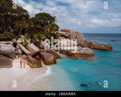 Tropische Inseln auf den Seychellen, Insel Praslins Seychellen, zwei Paare, die mit Palmen am tropischen Strand spazieren gehen Stockfoto