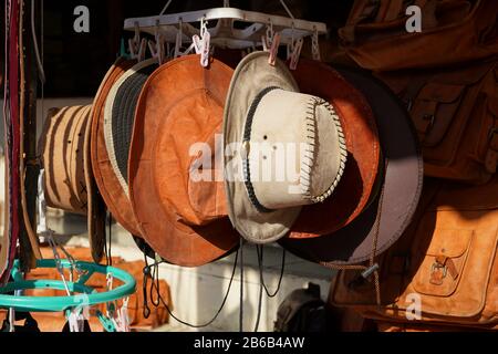 Cowboy-Weihnachten. Traditionelle amerikanische Westmütze aus reinem Leder, die im Freien bei Sonneneinstrahlung zum Verkauf angeboten werden. Sie hängen nebeneinander. Stockfoto