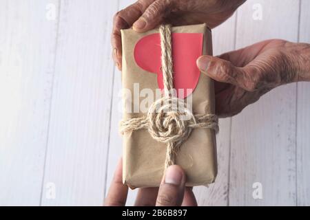 Seniorin schenkt jungen Mann Geschenkbox Stockfoto