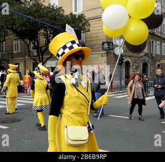 Rijeka, Kroatien, 23. Februar 2020. Eine lustige Frau mit gelbem Hut und Luftballons in der Hand, die während eines Karnevals die Straße hinunterläuft Stockfoto