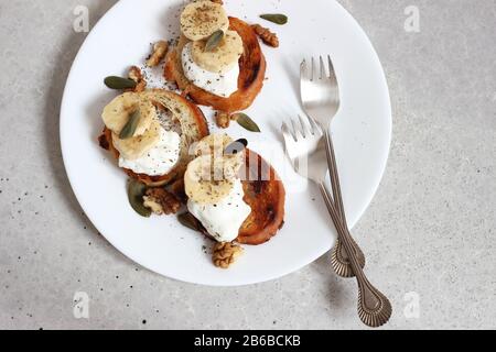 Blick auf die Tassen mit Bananenscheiben, Käse und Walnüssen auf Dem Teller. Lunch Food Konzept. Stockfoto