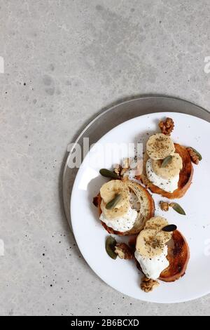 Blick auf Den Teller mit Toast mit Bananen, Mint, Käse und Walnüssen. Frühstück. Stockfoto